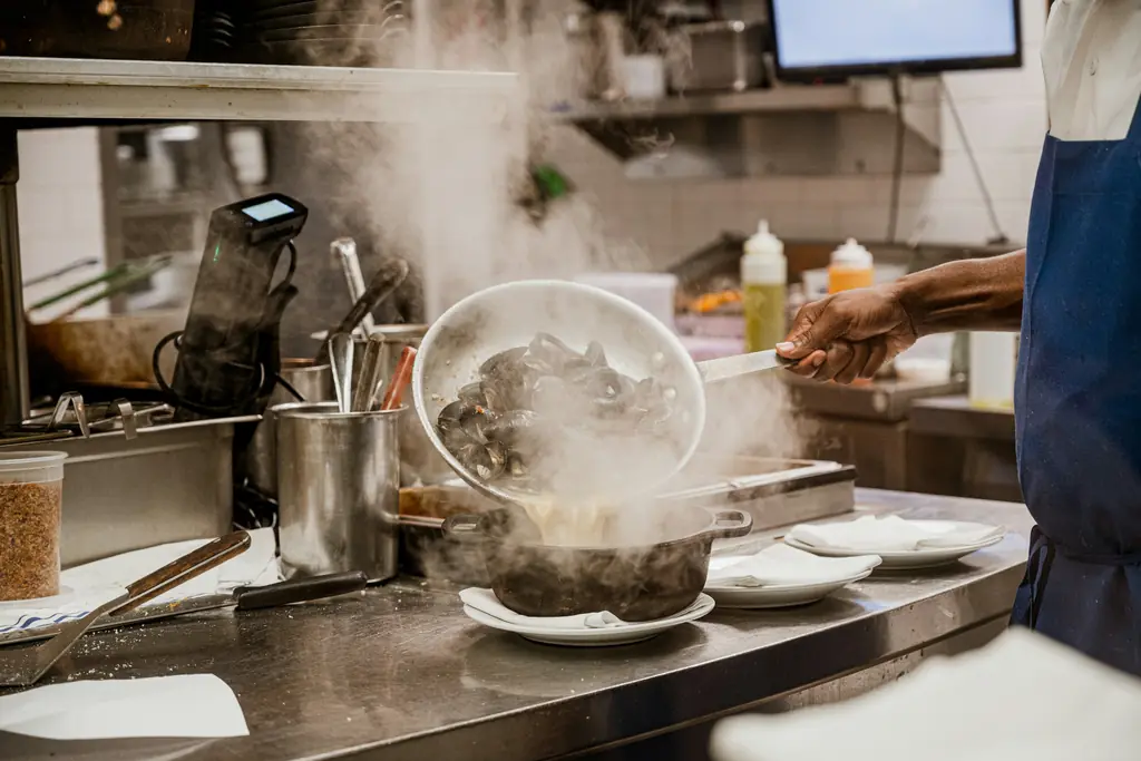 Una persona cocina en una cocina profesional llena de vapor.